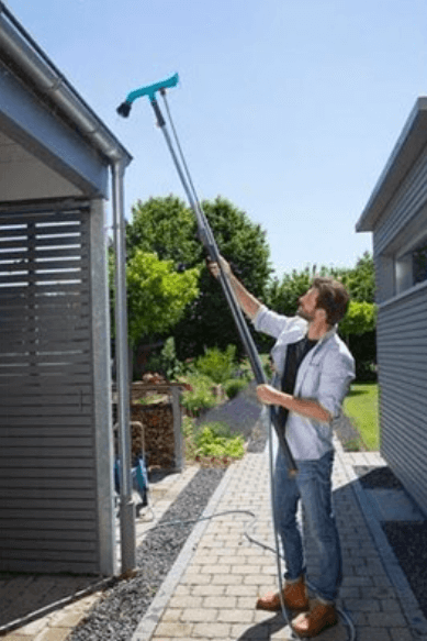 man using gutter cleaning tool to unblock his properties gutters